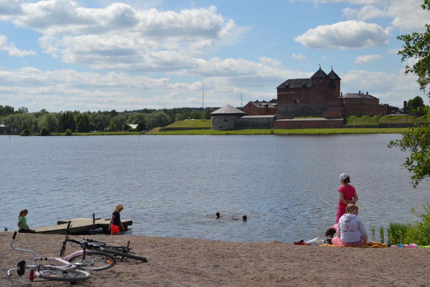 في الصورة امرأة تقف امام البحيرة، مقابل القلعة