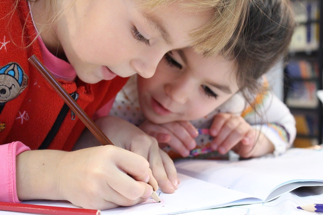 في الصورة طفلين يكتبون واجباتهم