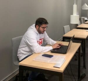 opiskelija istuu ja työskentelee tietokoneella