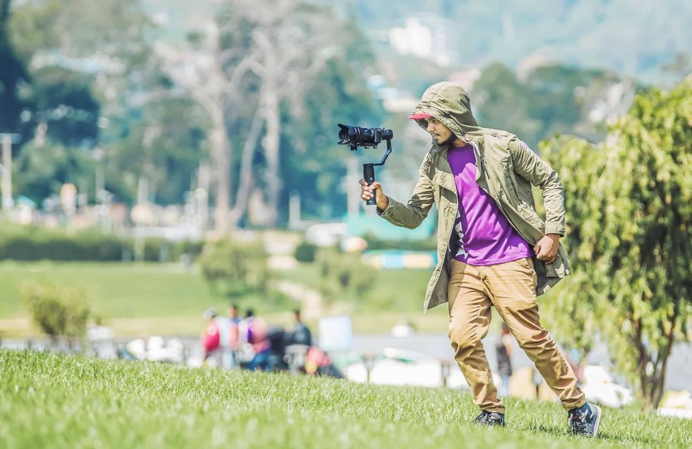 Mies kuvaa kameralla ulkona.