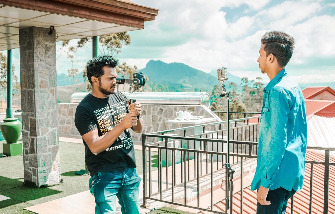 Ihminen kuvaa kameralla ulkona toista ihmistä.