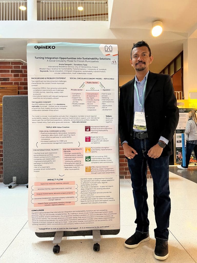 A person standing next to a big poster and looking at the camera.